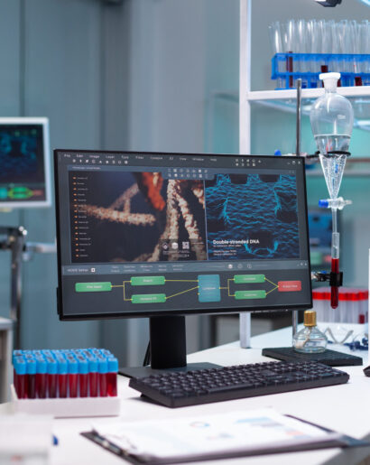 Empty laboratory with scientific monitor on desk. Nobody in chemical development space with professional tools, micro pipette, tray of vacutainers with blood, computer and microscope.